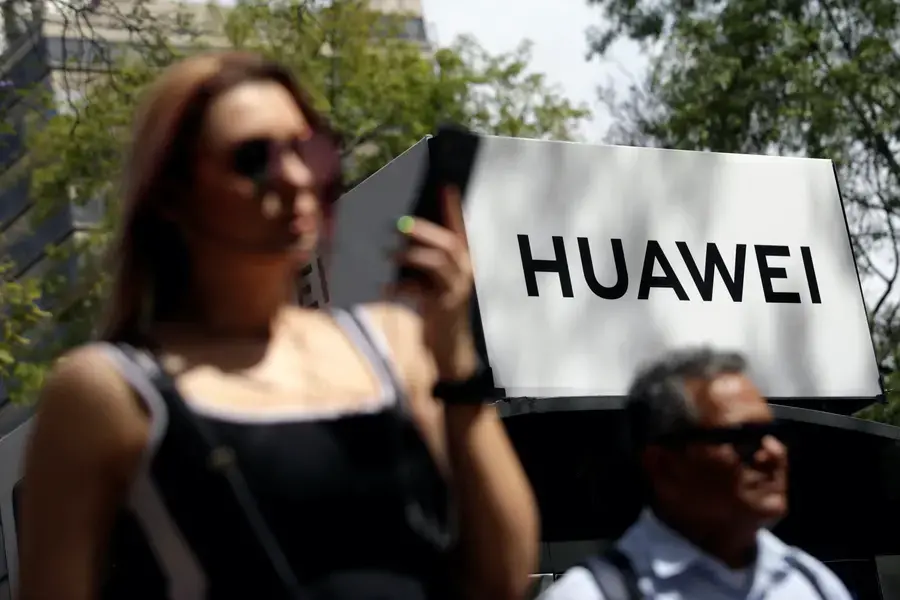 People walk past a Huawei company logo at a bus stop in Mexico City on February 22, 2019.