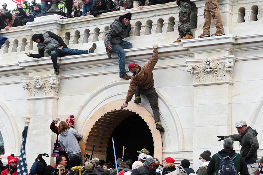 Supporters of U.S. President Donald Trump climb on walls at the U.S. Capitol.