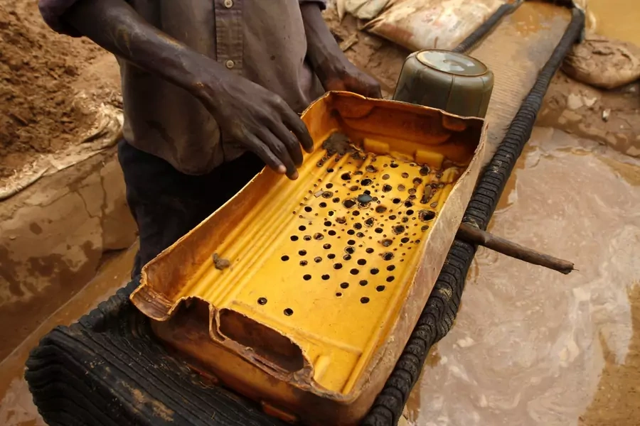 A man holds a plastic filter as he prepares to wash gold dust at a local goldmine in Bagega village in the northwestern state of Zamfara on August 14, 2013.