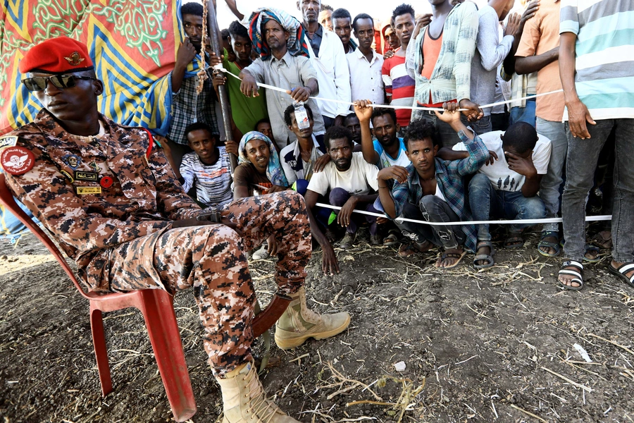 A Sudanese military officer keeps guard as Ethiopians who fled war in Tigray region, gather to receive relief supplies from the World Food Programme at the Fashaga camp on the Sudan-Ethiopia border in Al-Qadarif state, Sudan November 20, 2020.