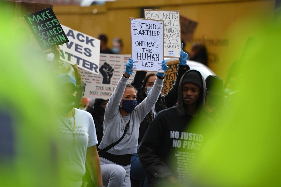 Protesters hold up placards as they “take a knee” in front of a police line at a Black Lives Matter demonstration outside the U.S. Embassy in London on June 7, 2020, during a weekend of global rallies against racism and police brutality. 