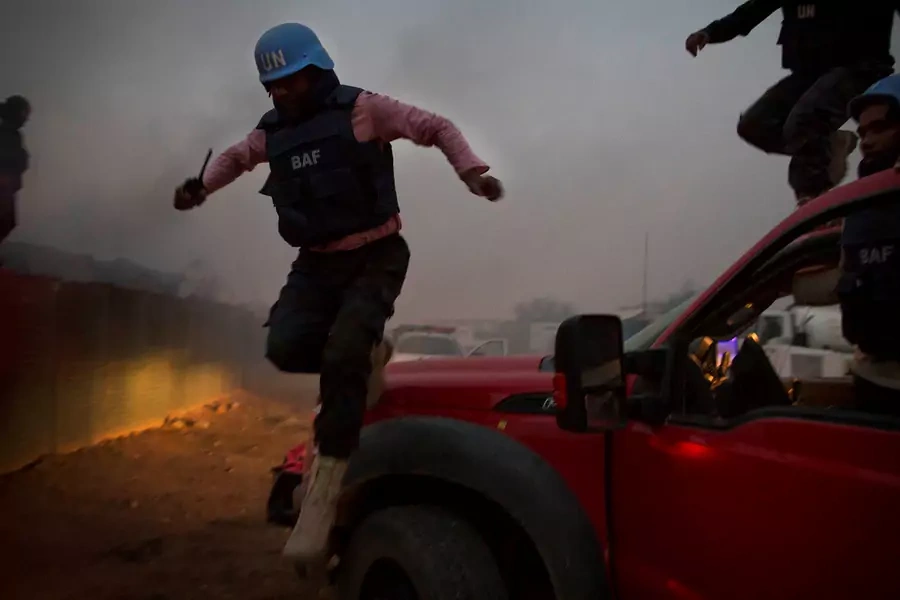 UN peacekeepers jump from vehicles at the MINUSMA base as they fight fires after a mortar attack in Kidal, Mali on June 8, 2017.