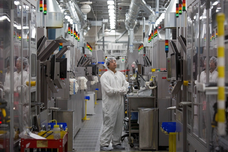 Production operator Sammy Blanco monitors multi colored lights atop automated machines at the SolarWorld solar panel factory in Hillsboro, Oregon, U.S.