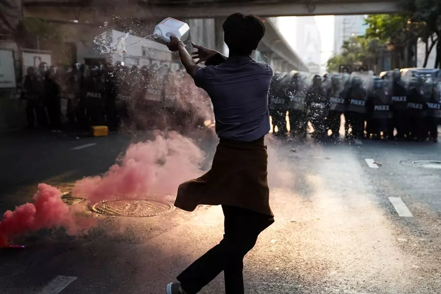 Anti-Thai government protester throws a liquid during a clash with riot police after protesters showed up at a rally for Myanmar's democracy outside the embassy, in Bangkok, Thailand on February 1, 2021. 