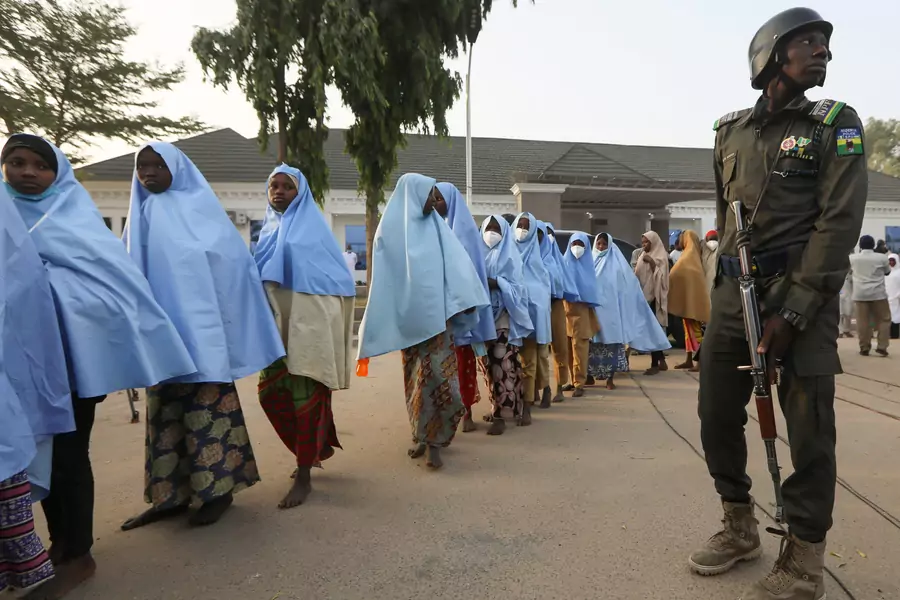 Girls who were kidnapped from a boarding school in the northwest Nigerian state of Zamfara walk in line after their release, as a police officer stands close in Zamfara, Nigeria on March 2, 2021.