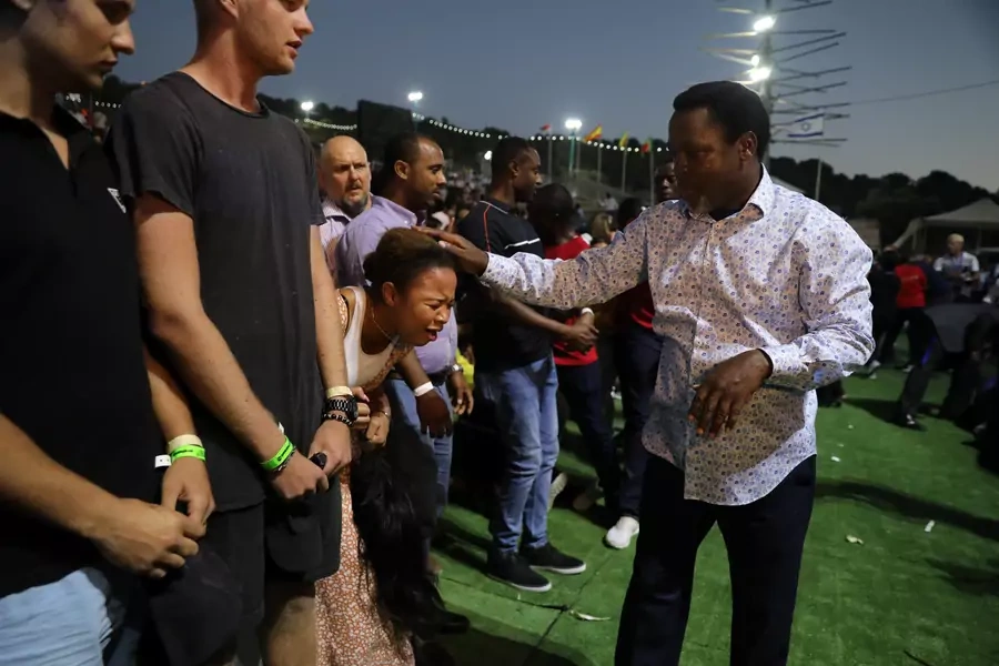 A woman reacts as her head touched by T.B. Joshua, a Nigerian evangelical preacher as he leads a religious retreat on Mount Precipice, Nazareth, northern Israel on June 23, 2019.