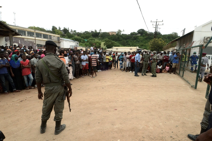 Security officials stand guard as people wait for friends and relatives as a ship carrying more than 1,000 people fleeing an attack claimed by Islamic State-linked insurgents on the town of Palma, docks in Pemba, Mozambique on April 1, 2021.