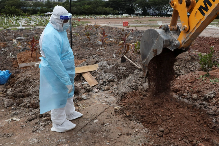 A cemetery worker wearing a protective suit helps to bury a victim of the coronavirus disease (COVID-19) at a cemetery in Shah Alam, Malaysia, July 14, 2021.