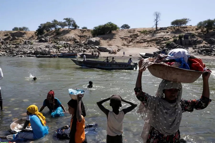 Refugees stand on the Ethiopian bank of a river that separates Sudan from Ethiopia near the Hamdeyat refugees transit camp, which houses Ethiopian refugees fleeing the fighting in the Tigray region, on the Sudan-Ethiopia border on November 30, 2020. 