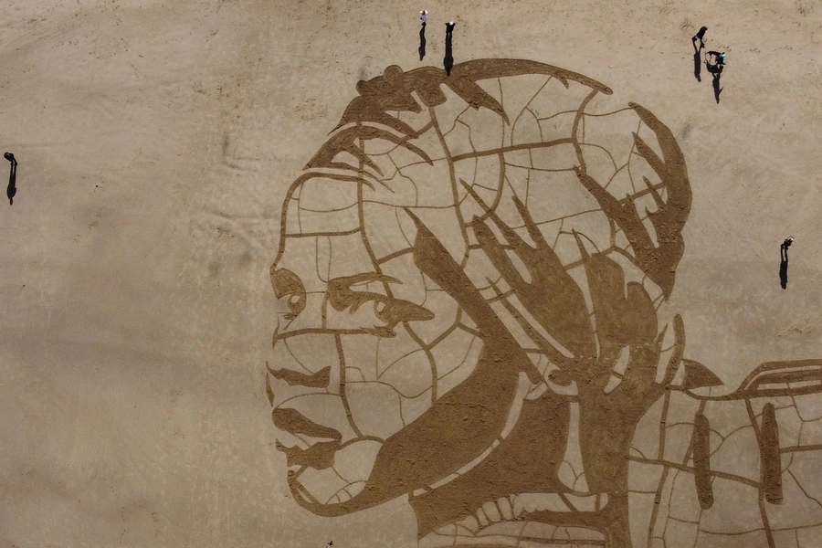 WaterAid and Sand In Your Eye's giant sand drawing, seen on Whitby Beach, Britain, shows a child carrying water on dry, cracked ground next to the rising tide to highlight the effect of climate change on people's access to water on March 15, 2021.