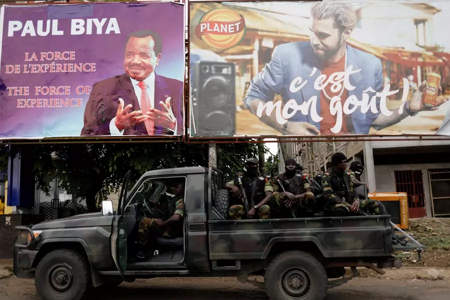 Cameroonian elite Rapid Intervention Battalion members sit on their military vehicle under an electoral billboard of Cameroon President Paul Biya during a patrol in the south west city of Buea, Cameroon on October 4, 2018.