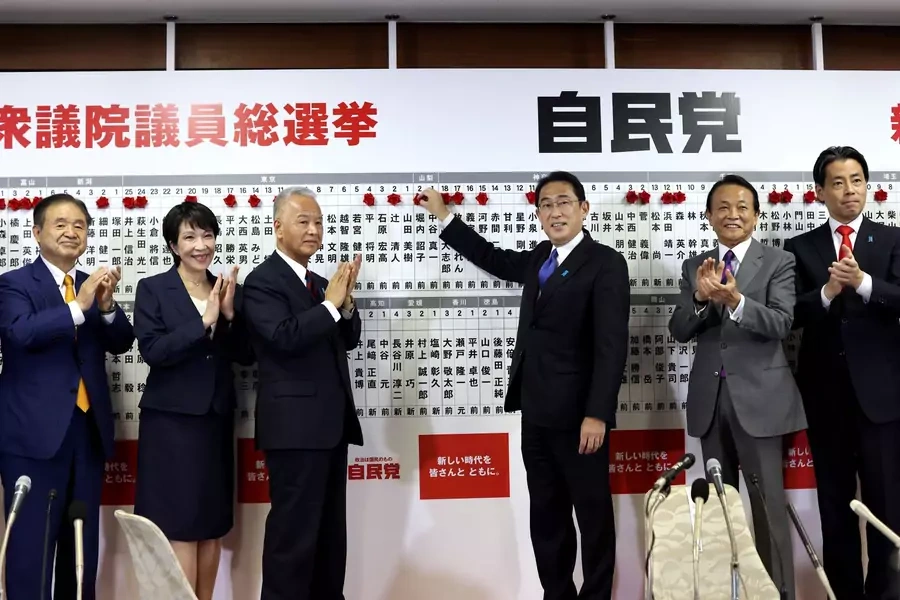 Japan's Prime Minister and ruling Liberal Democratic Party leader Fumio Kishida poses with key party members as he puts rosettes on a board with names of successful general election candidates, at the party headquarters, in Tokyo, Japan, October 31, 2021.