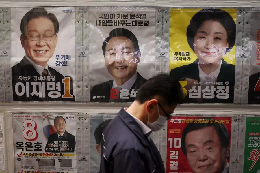 A man stands in front of posters of candidates for the upcoming March 9 presidential election as he queues to cast his early vote at a polling station in Seoul, South Korea on March 4, 2022.
