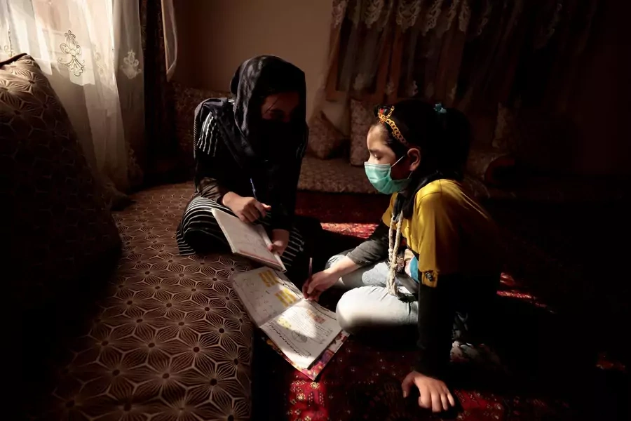 Sahar, 17, helps her sister, Hadia, 10, with her homework after school at their home in Kabul, Afghanistan on October 26, 2021.