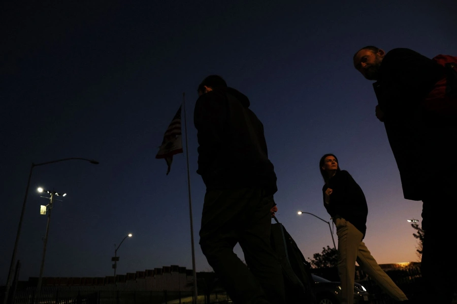 Ukrainian people seeking asylum in the United States amid Russia's invasion of Ukraine, walk after arriving at the PedWest border crossing to a volunteer welcome center at the San Ysidro Port of Entry in San Diego, California on April 12, 2022.