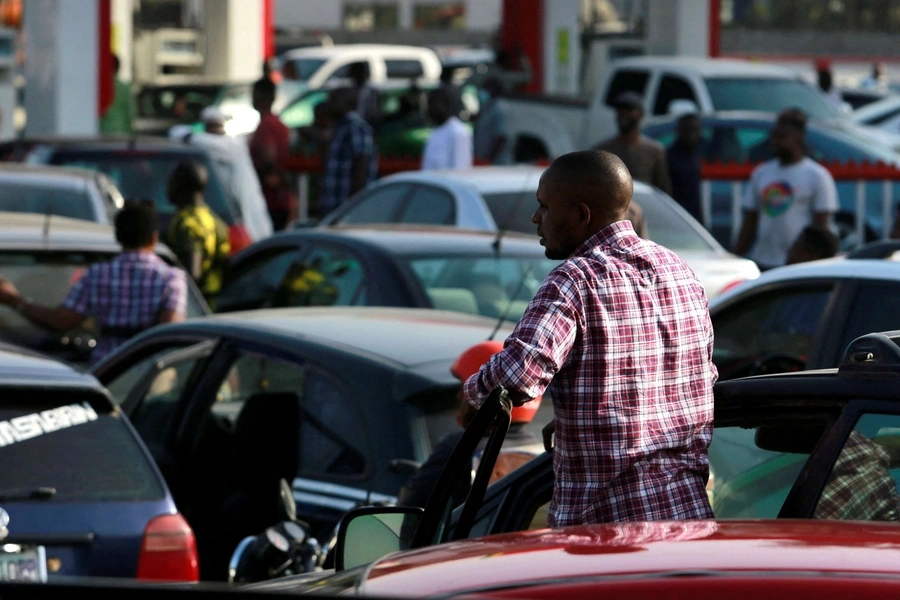 A Nigerian man gazes from his car in the midst of several vehicles seeking to fill gas at a station in Abuja. 