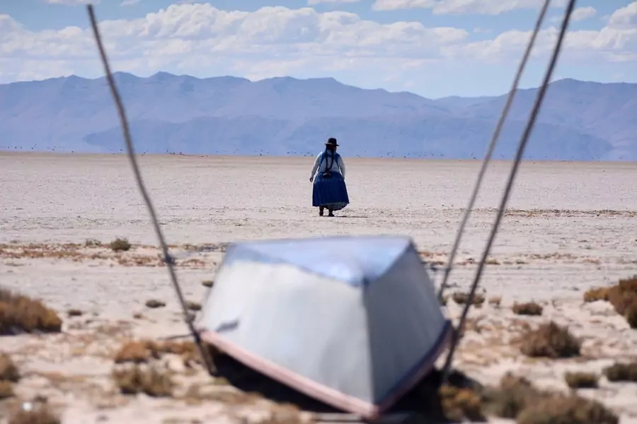 Cristina Mamani walks near an unused boat in Lake Poopo, Bolivia's second largest lake which has dried up due to water diversion for regional irrigation needs and a warmer, drier climate, according to local residents and scientists on July 24, 2021. 
