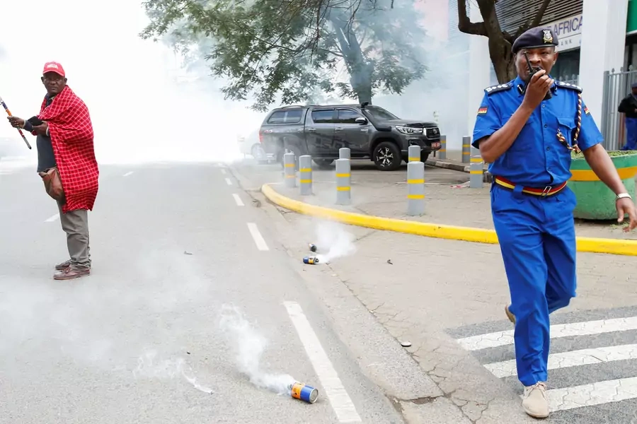 A policeman calls for backup as Jonathan Mpute Ole Pasha, national coordinator of the Maa Unity Agenda (MUA) group in Kenya, stands amid tear gas during a Maasai protest against the eviction of their compatriots in Tanzania on June 17, 2022.