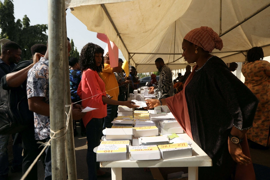 A woman presents a paper to an INEC worker during the collection of permanent voters cards at the INEC office in Abuja, Nigeria on December 13, 2022