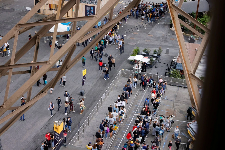 Sightseers wait in line for the Eiffel Tower after it reopened to tourists following a national lockdown. 