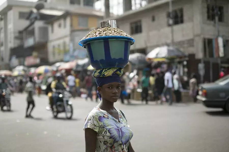 Sierra Leonen woman carries a pot of peanuts on her head in Freetown.