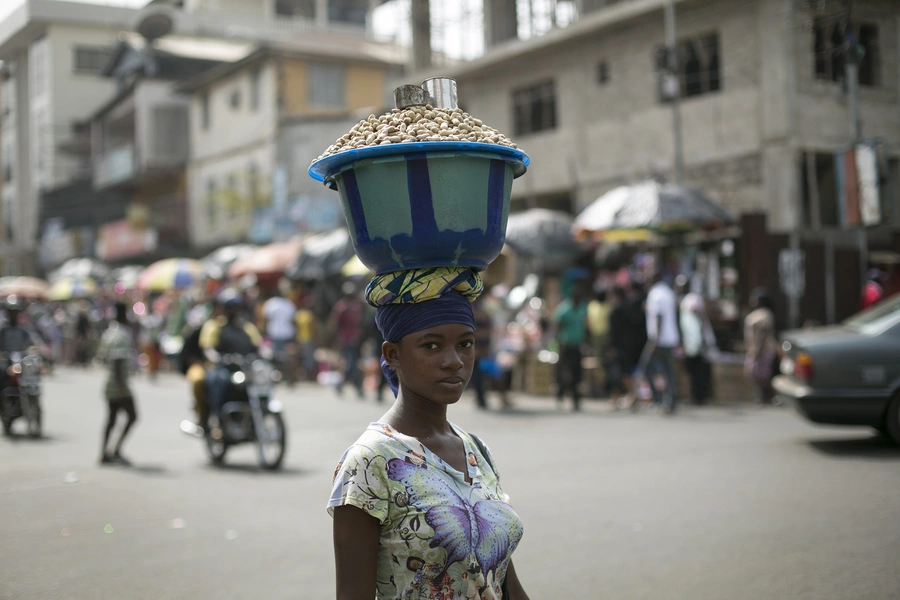 Sierra Leonen woman carries a pot of peanuts on her head in Freetown.