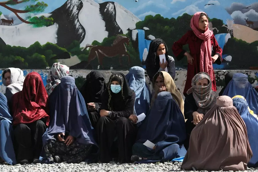 Afghan women wait to receive a food package at a distribution center in Kabul.