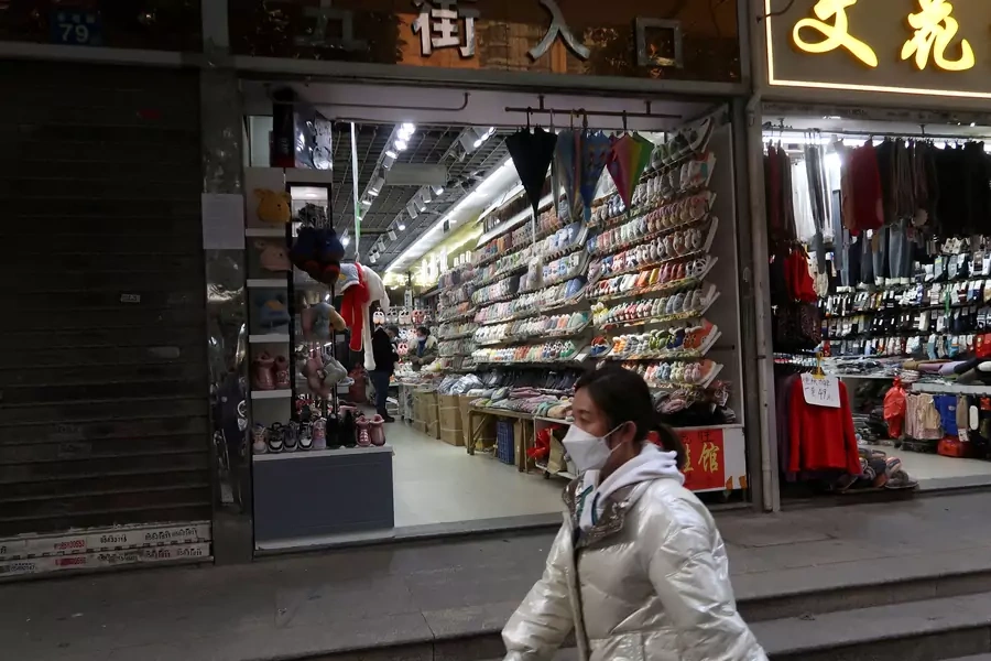 A person walks past shops, after the government eased curbs on the coronavirus disease (COVID-19) control, in Wuhan, Hubei province, China December 10, 2022. REUTERS/Martin Pollard