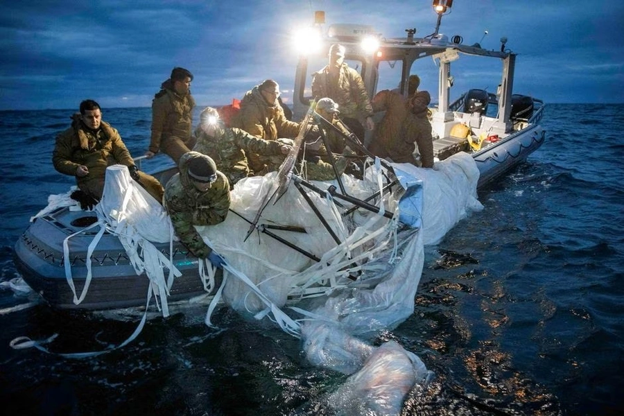 Soldiers pull a portion of a Chinese spy balloon shot down over the ocean into a small dinghy off the coast of South Carolina.