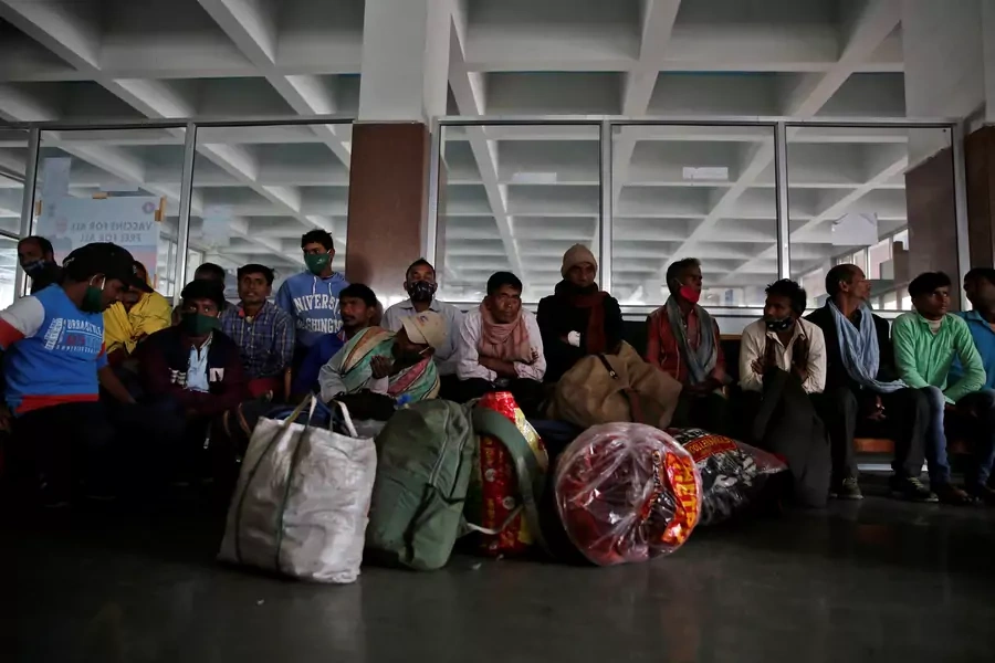 Indian migrant workers wait inside a railway station to board trains to their home states