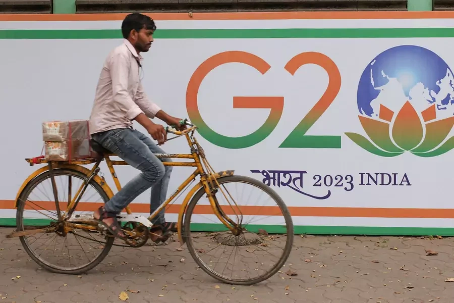 A man rides a bicycle past a poster advertising India's G20 presidency on a street in Mumbai, India.