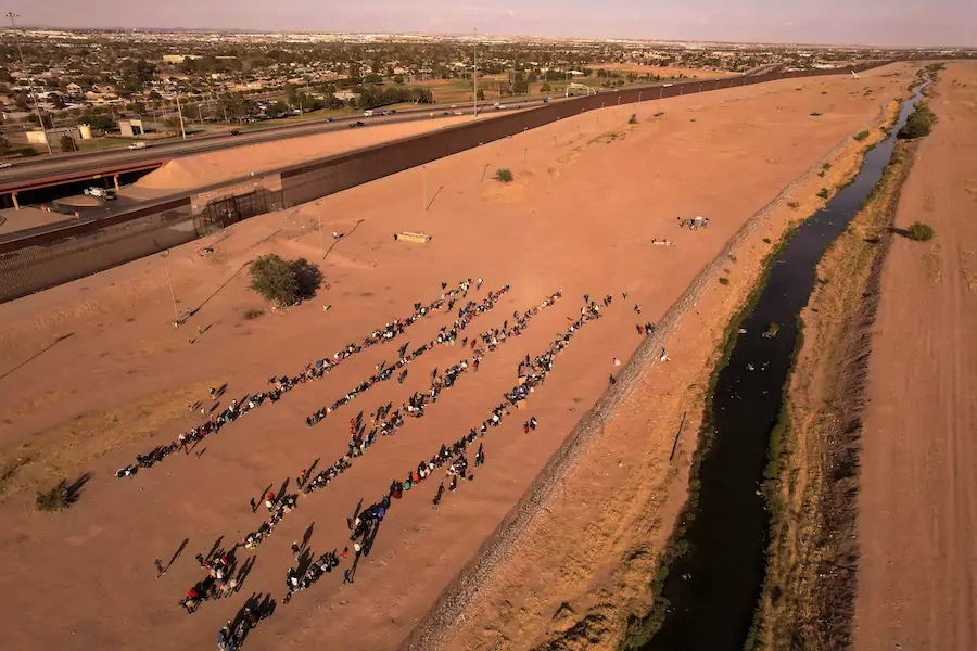 Migrants stand near the border wall after crossing the Rio Bravo river with the intention of turning themselves in to the U.S. Border Patrol agents, as seen from Ciudad Juárez, Mexico.