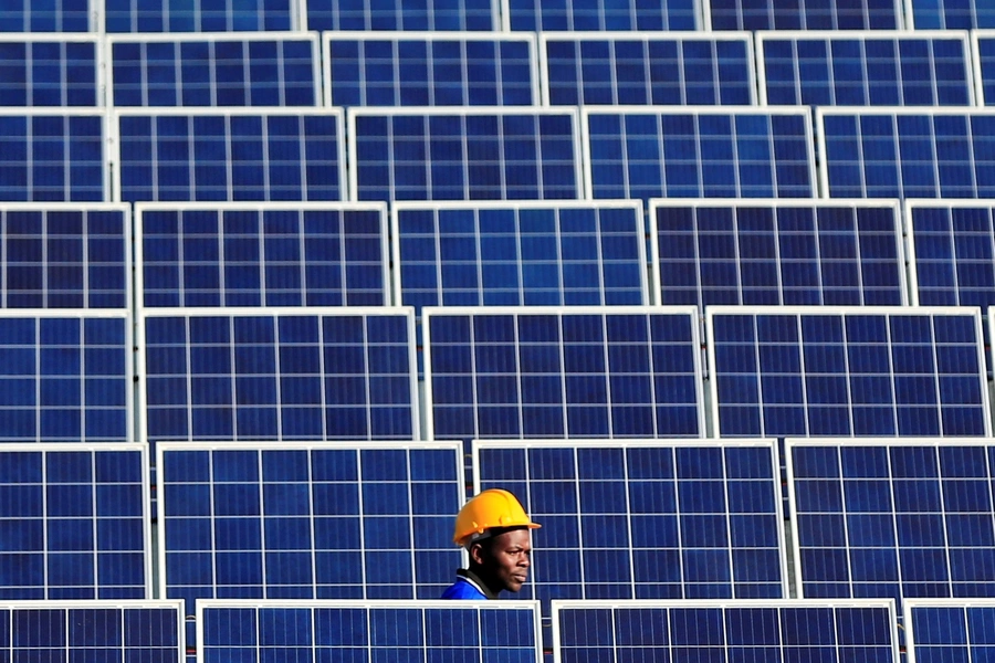 A worker walks between solar panels at Centragrid power plant in Nyabira, Zimbabwe.