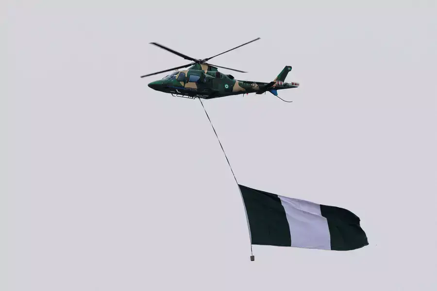 A Nigerian military helicopter carries a Nigerian flag during the swearing-in ceremony of Nigeria's President Bola Tinubu in Abuja, Nigeria on May 29, 2023. 