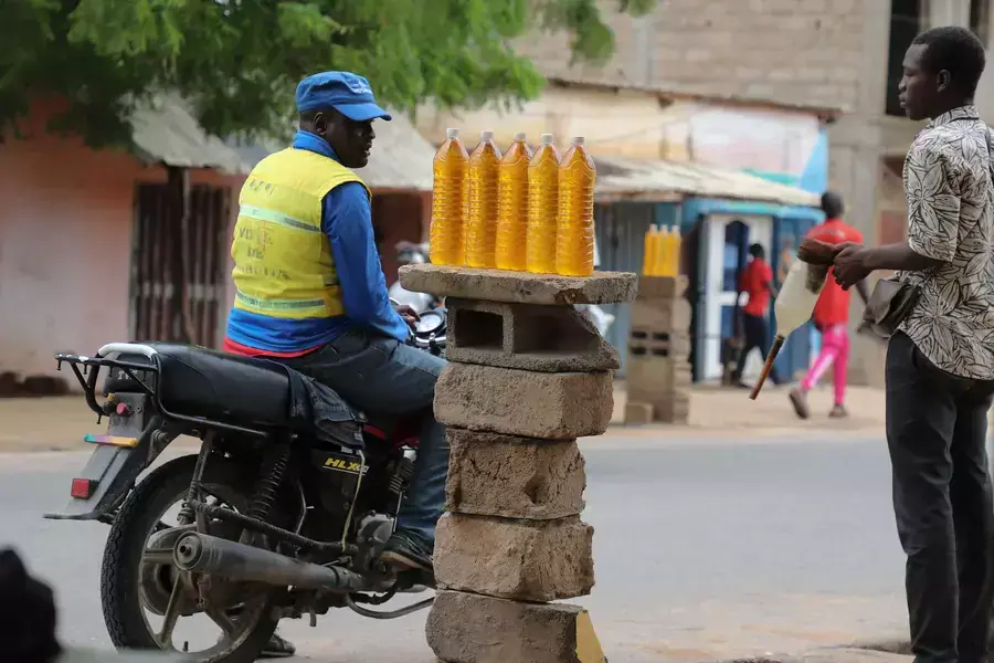 A motorcycle taxi man waits for his bike to be refuelled with smuggled Nigerian fuel in Garoua, Cameroon on June 21, 2023.