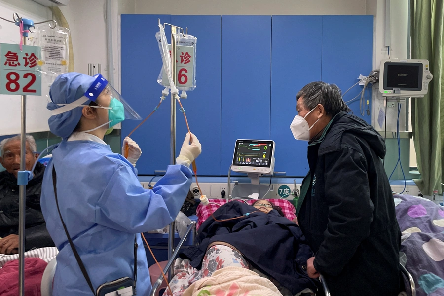 A medical worker checks the IV drip treatment of a patient lying on a bed in the emergency department of a hospital, amid the coronavirus disease (COVID-19) outbreak in Shanghai, China, January 5, 2023. 