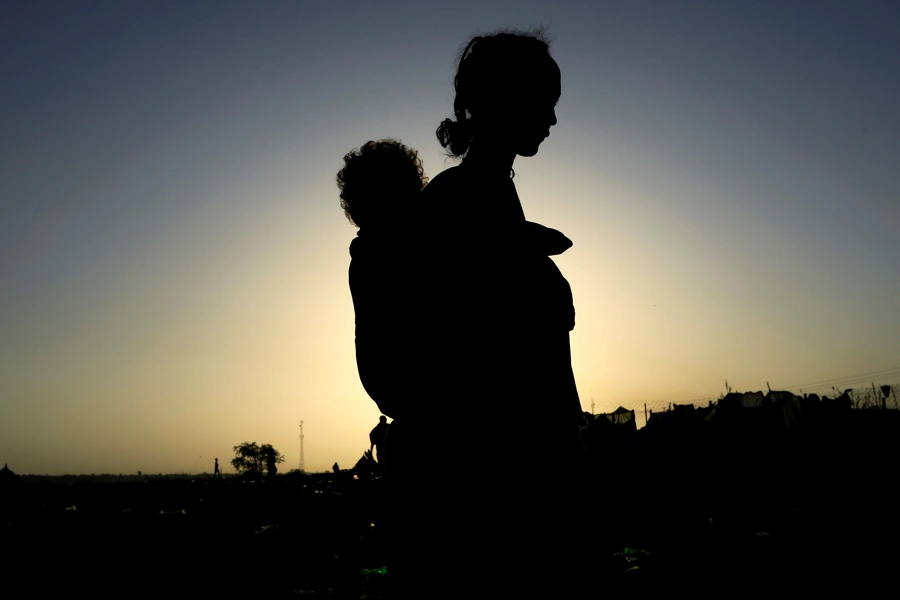 An Ethiopian woman who fled the ongoing fighting in Tigray region, carries her child near the Setit river on the Sudan-Ethiopia border in Hamdayet village in eastern Kassala state, Sudan November 22, 2020