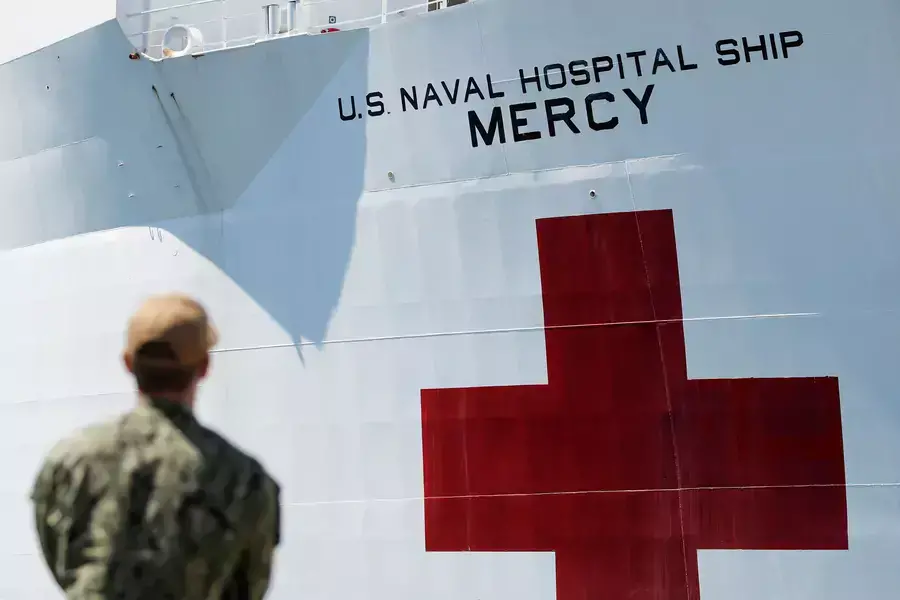 A member of the army looks on as the USNS Mercy, a Navy hospital ship, departs the Naval Station San Diego to aid local medical facilities dealing with COVID-19 patients, in San Diego, California, on March 23, 2020.