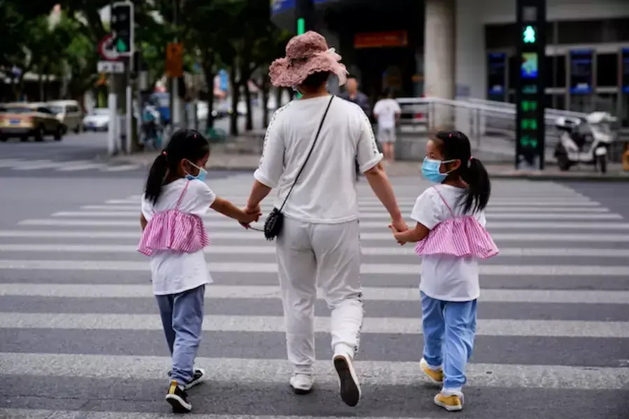 A mother walks across the street with her daughters in Shanghai, China.
