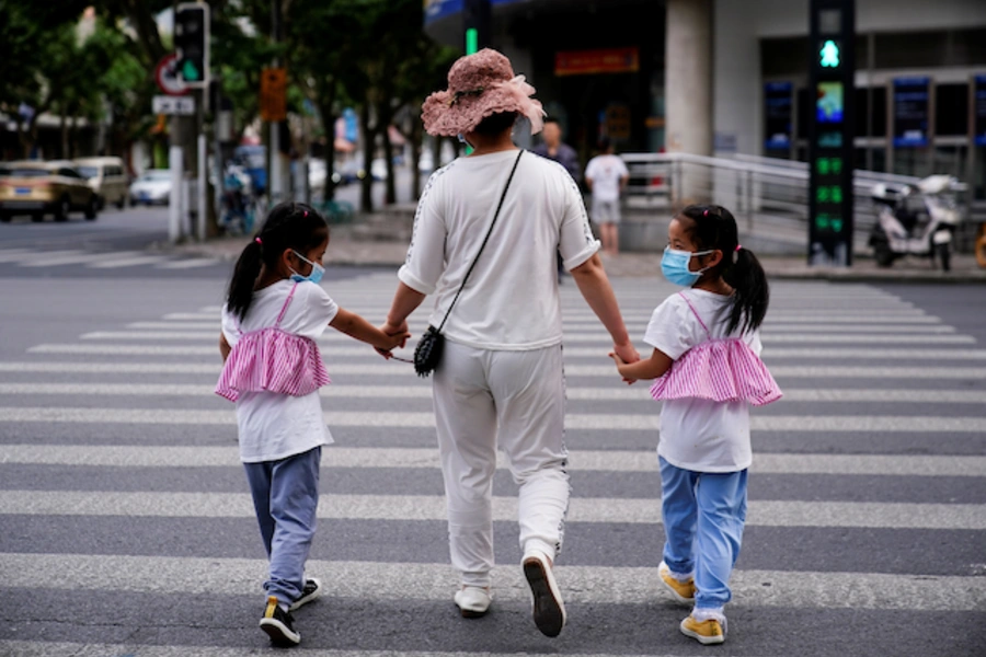 A mother walks across the street with her daughters in Shanghai, China.