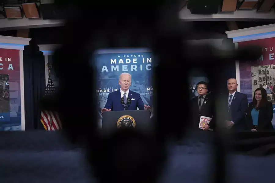 U.S. President Joe Biden speaks with a Made in America poster displayed prominently in the background, highlighting his administration's undertaking of industrial policy.
