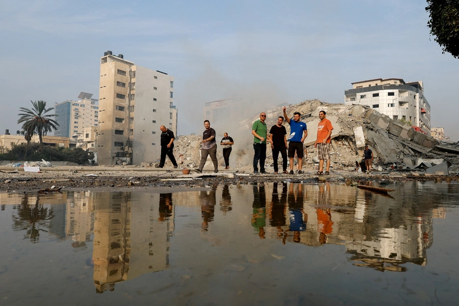 Palestinians inspect the ruins of Watan Tower, which was destroyed in Israeli strikes, in Gaza City