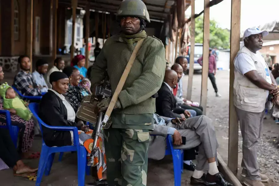 A Congolese soldier stands guard as civilians gather to enroll with the electoral commission as voters in Goma, North Kivu province of the Democratic Republic of Congo on February 16, 2023.