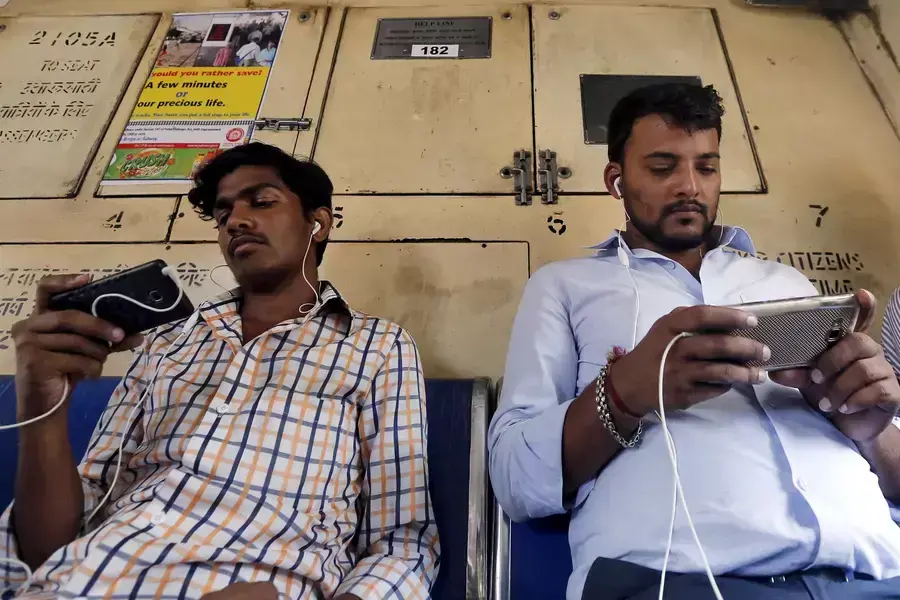 Commuters watch videos on their mobile phones as they travel in a suburban train in Mumbai, India.