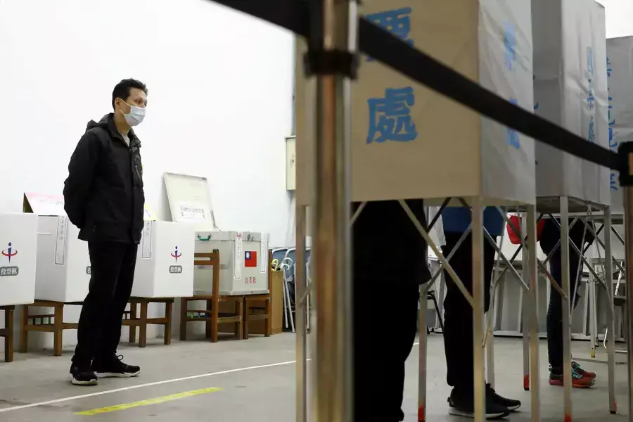 An electoral worker watches voters at a polling station in Taipei, Taiwan, on December 18, 2021.