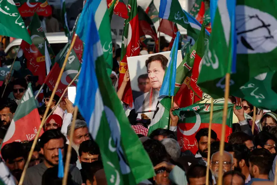 A portrait of the former Prime Minister Imran Khan is seen amid flags of Pakistan Tehreek-e-Insaf (PTI) and the Jamat-e-Islami (JI) political parties as supporters attend a joint protest outside the Pakistan Electoral Commission on February 10, 2024.