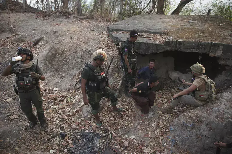 Members of the Karen National Liberation Army and People's Defense Force examine two arrested soldiers after they captured an army outpost in the southern part of Myawaddy township in Kayin state, Myanmar, on March 11, 2024.