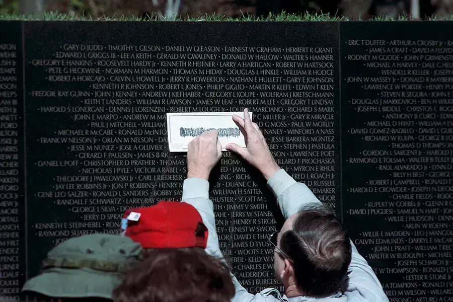 A man traces the name of Charles McMahon on a piece of paper at the Vietnam Veterans Memorial in Washington, DC, on November 11, 1989.