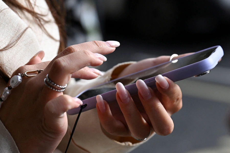 A woman holds her phone on the street in Westminster, in London, Britain, October 11, 2024.