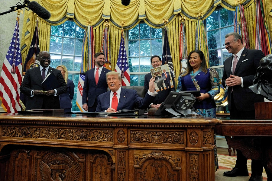 U.S. President Donald Trump holds a picture of himself with Rwanda's Foreign Minister Olivier Nduhungirehe, during a meeting with Nduhungirehe and the Democratic Republic of the Congo's Foreign Minister Therese Kayikwamba Wagner on June 27, 2025. 